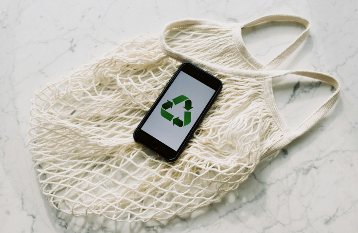 Circular economy represented by recycling symbol on iphone and reusable shopping bag